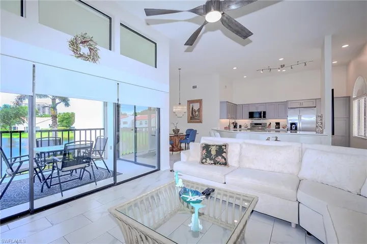 Living area with a towering ceiling, ceiling fan, light tile patterned floors, and recessed lighting