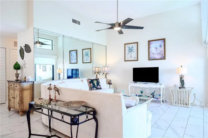 Living area featuring light marble finish flooring, a towering ceiling, and ceiling fan