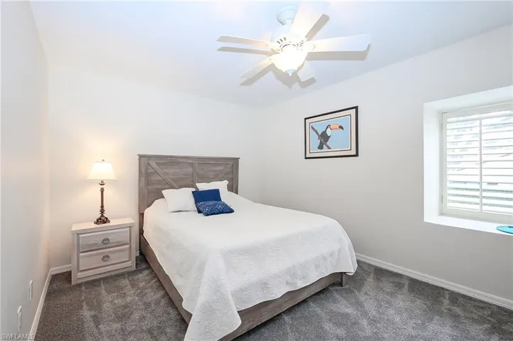 Bedroom with dark colored carpet and a ceiling fan