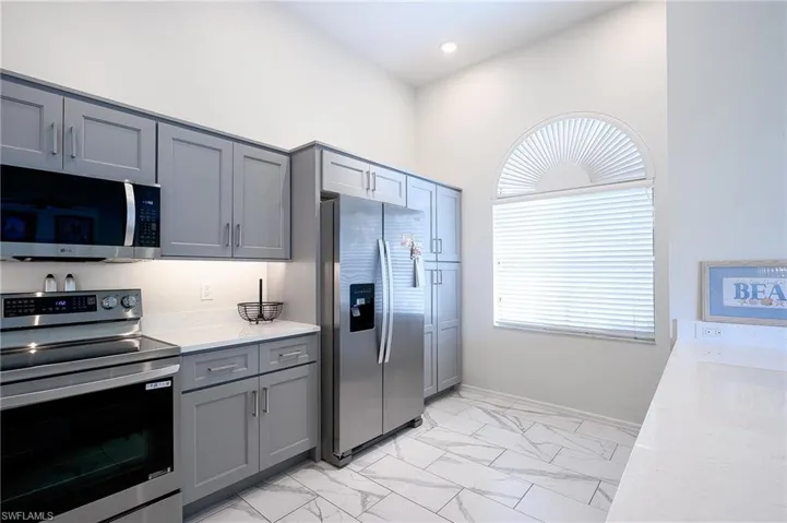 Kitchen with new  appliances with stainless steel finishes, light tile patterned flooring, and light stone countertops