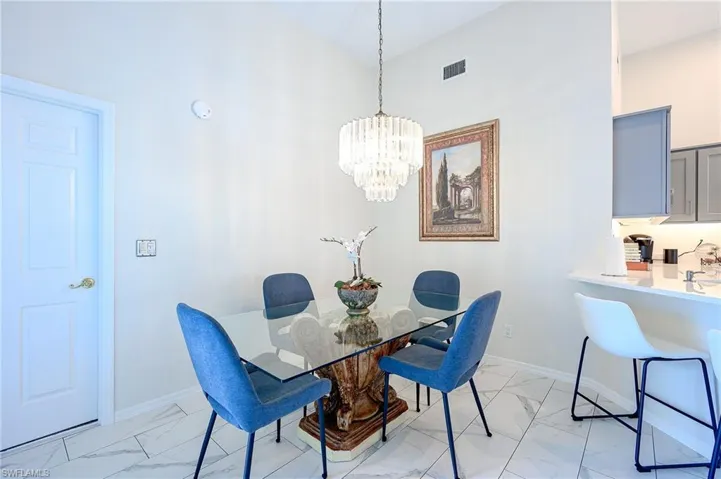 Dining space with light marble finish floors and a chandelier