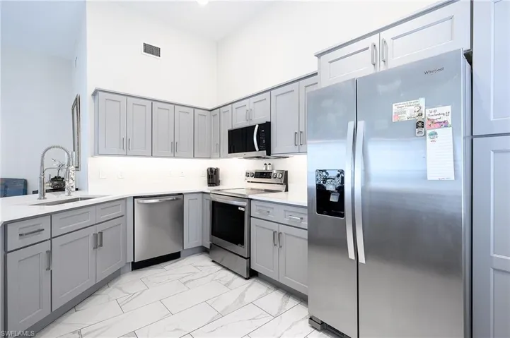 New updated Kitchen and appliances, sink, light tile patterned flooring, gray cabinets, and a towering ceiling