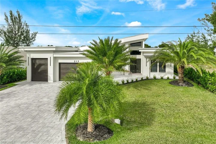 View of front of home featuring stucco siding, a front yard, an attached garage, and decorative driveway