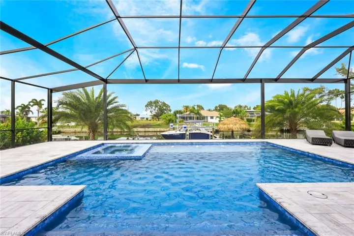 Swimming pool featuring a water view, a lanai, a patio, an in-ground hot tub, and a sunroom