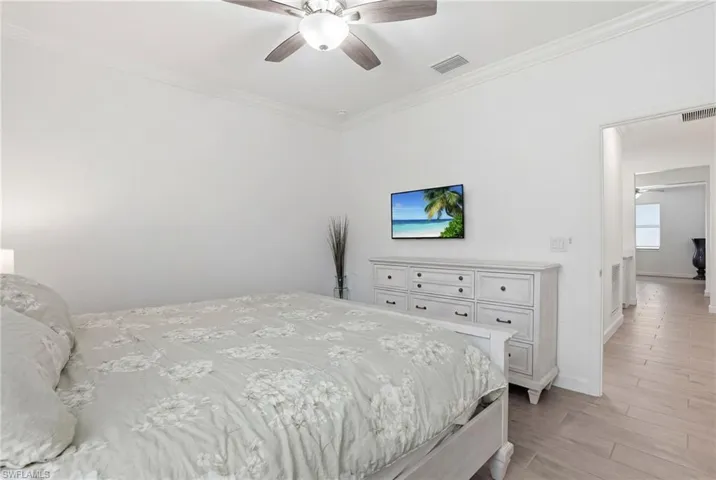 Bedroom with ornamental molding, light wood-style flooring, and a ceiling fan