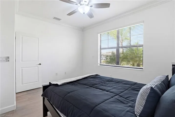 Bedroom with ornamental molding, wood finished floors, and a ceiling fan
