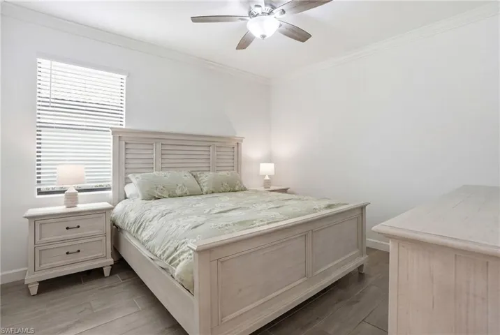 Bedroom with wood finish floors, ornamental molding, and a ceiling fan