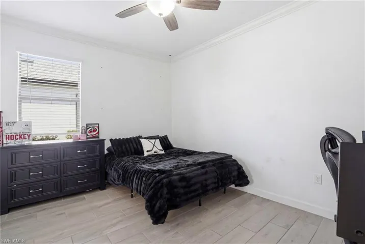 Bedroom with wood tiled floors, crown molding, and a ceiling fan