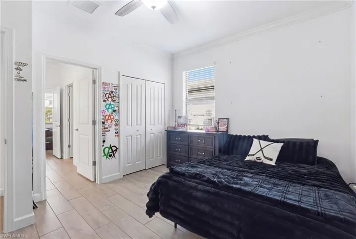 Bedroom featuring wood finish floors, crown molding, a closet, and a ceiling fan