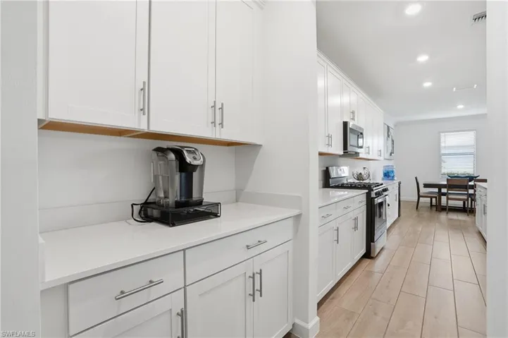 Kitchen featuring stainless steel appliances, white cabinetry, wood tiled floors, recessed lighting, and light stone countertops