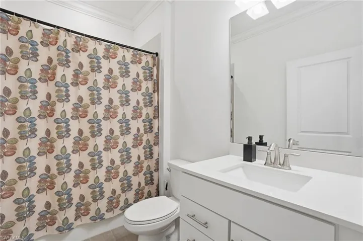 Full bath with crown molding, vanity, and shower / tub combo with curtain