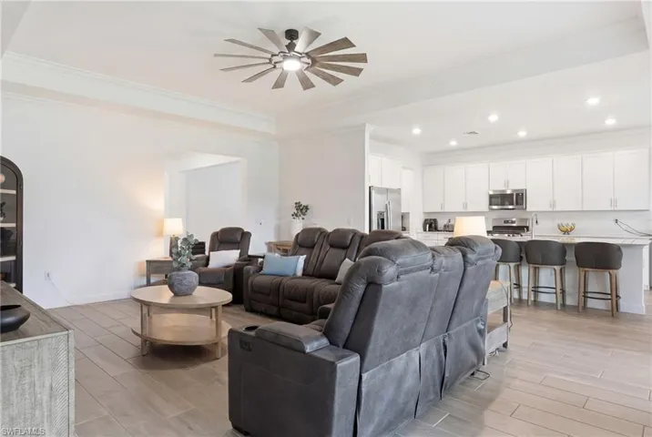 Living area featuring wood tiled floors, ceiling fan, crown molding, and recessed lighting