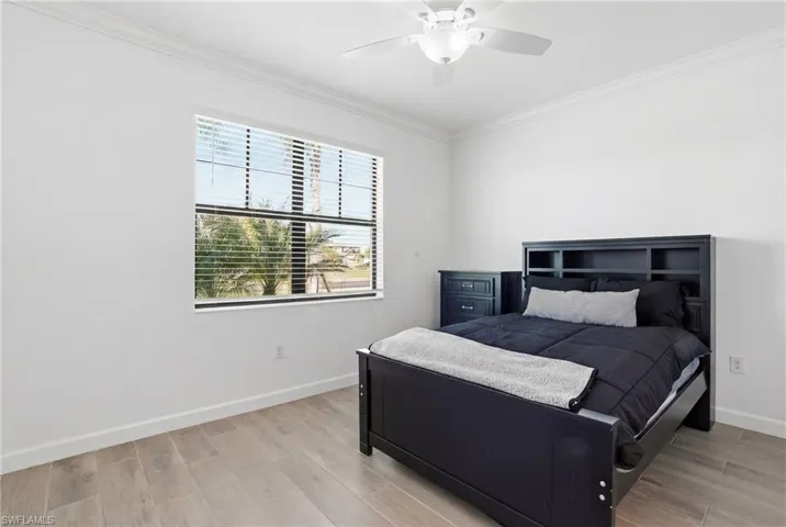 Bedroom with light wood-type flooring, crown molding, and ceiling fan