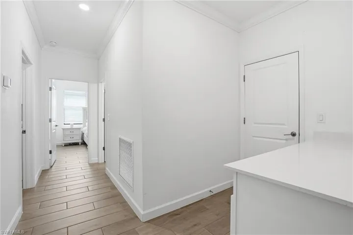 Hallway with light wood finished floors and crown molding