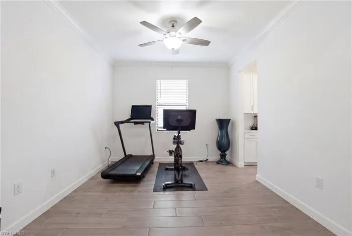 Exercise room with light wood-style floors, crown molding, and a ceiling fan