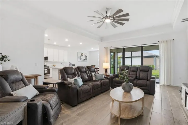 Living room with wood tiled floors, crown molding, a tray ceiling, a ceiling fan, and recessed lighting