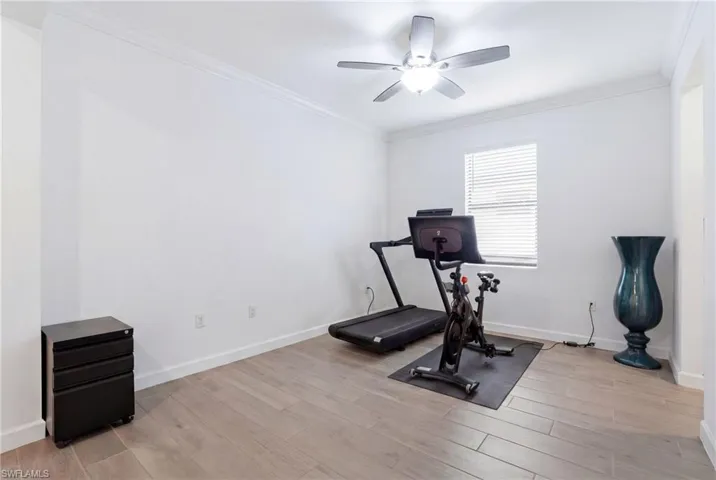 Workout room with ornamental molding, light wood finished floors, and a ceiling fan