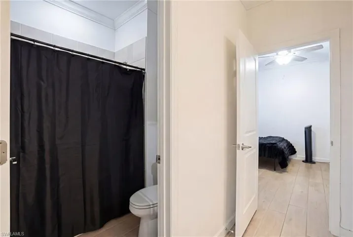 Full bathroom with crown molding, curtained shower, light wood-type flooring, ensuite bath, and a ceiling fan