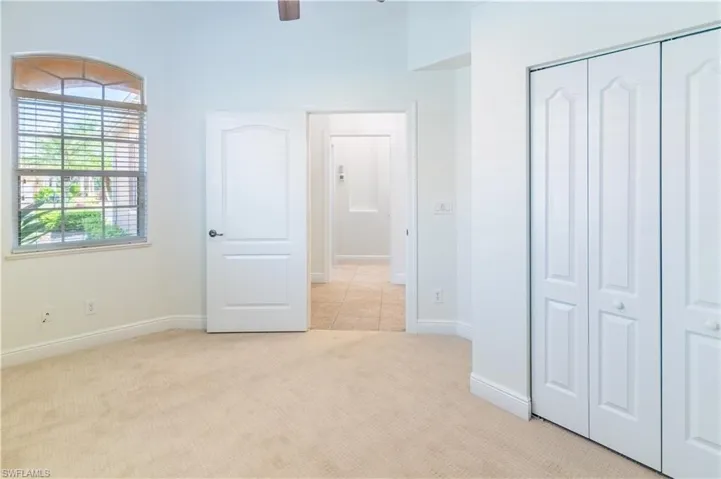 Unfurnished bedroom featuring light colored carpet, a closet, and a ceiling fan