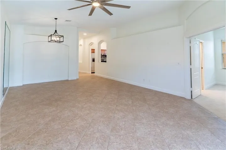 Spare room featuring ceiling fan, arched walkways, and a chandelier