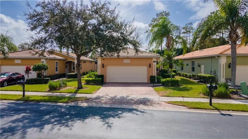 View of front facade with stucco siding, decorative driveway, a tile roof, and a front yard