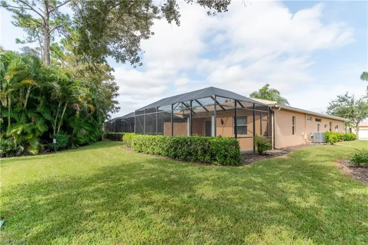 Rear view of house featuring glass enclosure, a sunroom, a yard, and stucco siding