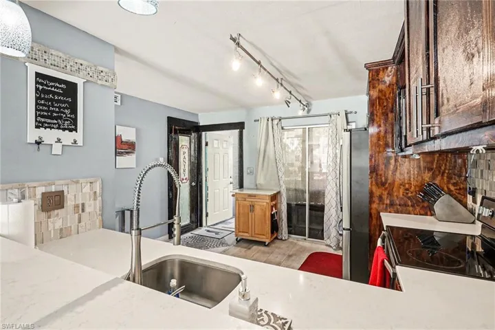 Kitchen with stainless steel appliances, tasteful backsplash, and light stone counters