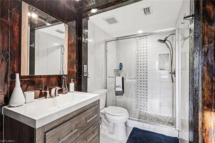 Full bath with tile walls, vanity, and a stall shower