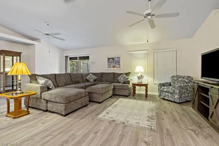 Living room with light wood-type flooring, ceiling fan, and lofted ceiling