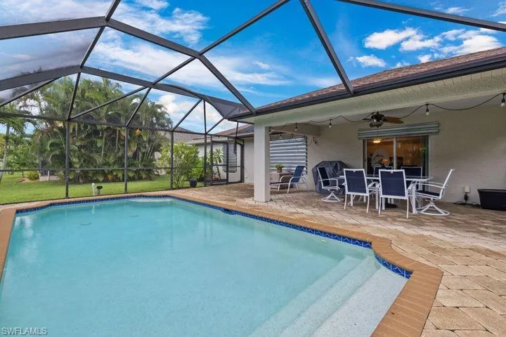 View of swimming pool with ceiling fan, a patio, and a lanai