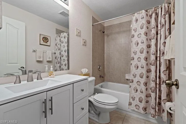 Full Guest bathroom with shower / bath combo with shower curtain, tile patterned floors, a textured ceiling, vanity, and toilet