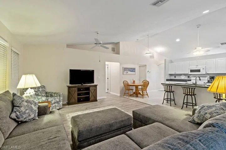Living room with ceiling fan, high vaulted ceiling, sink, and light hardwood / wood-style floors