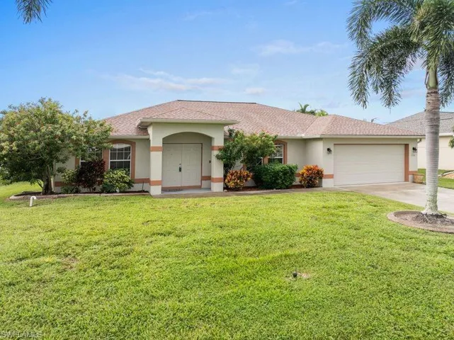 Ranch-style home with a garage and a front lawn