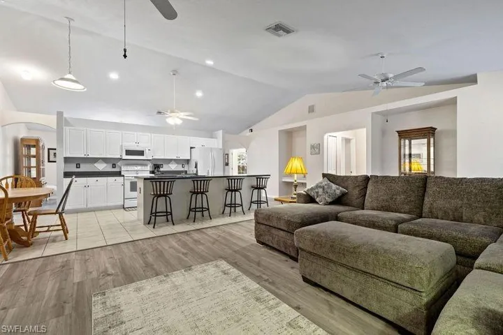 Living room featuring plenty of natural light, ceiling fan, light wood-type flooring, and lofted ceiling