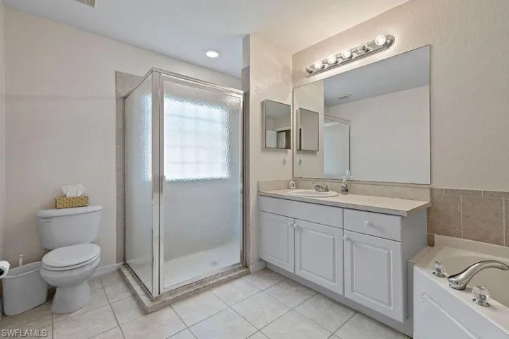 Full master bathroom with tile patterned flooring, toilet, independent shower and bath, and vanity