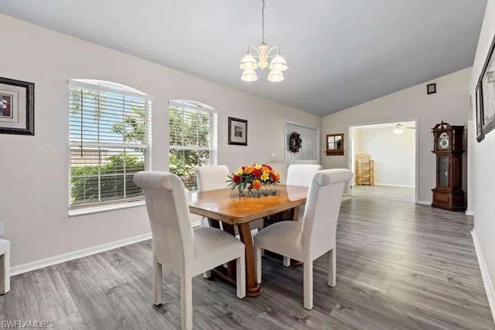Dining area featuring lofted ceiling, ceiling fan with notable chandelier, and hardwood / wood-style flooring