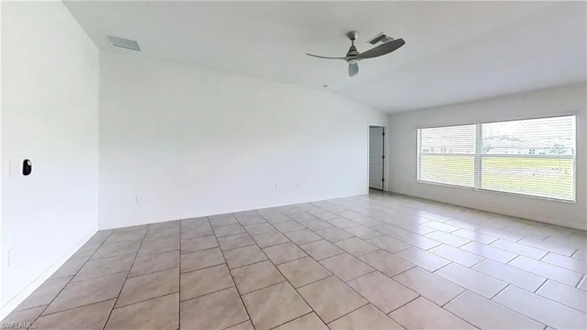 Spacious room featuring vaulted ceilings, tile flooring, and a modern ceiling fan