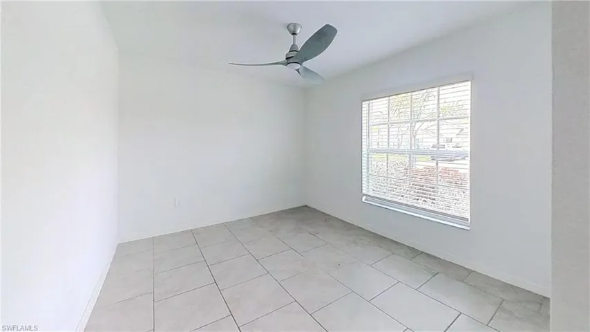 Neutral wall finishes, a modern ceiling fan, and tile flooring define this bright room
