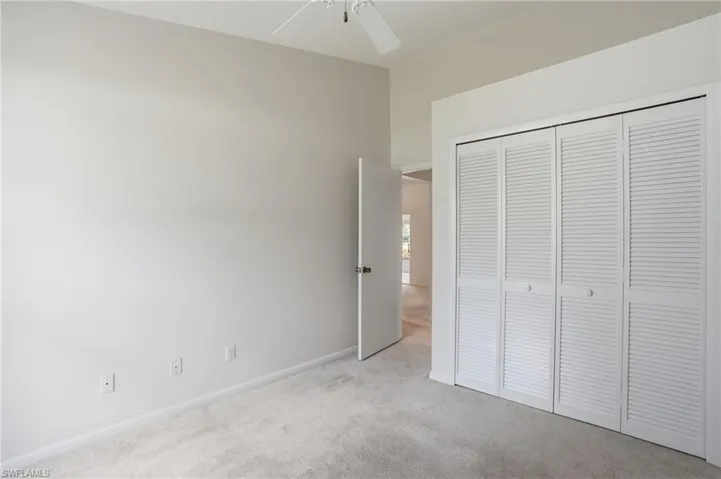Plush carpet flooring, neutral wall tones, and a ceiling fan with light fixture