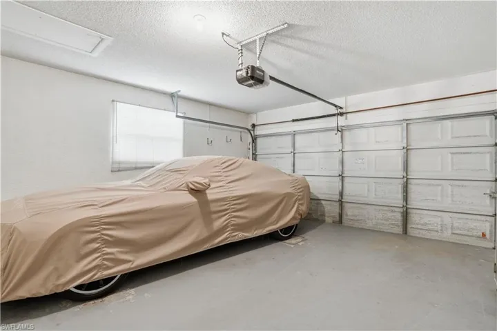 Two-car garage featuring a garage door opener system, overhead lighting, and a single window with blinds