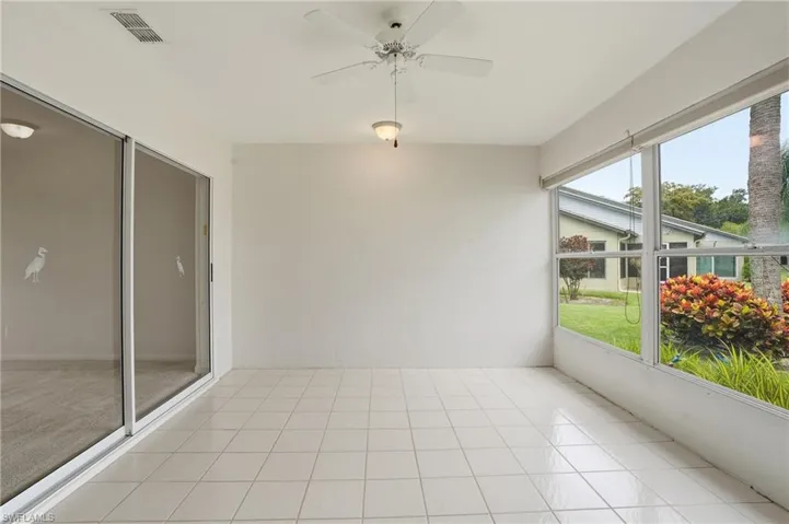 Screened patio featuring white tile flooring, ceiling fan, recessed lighting, and expansive windows overlooking landscaping