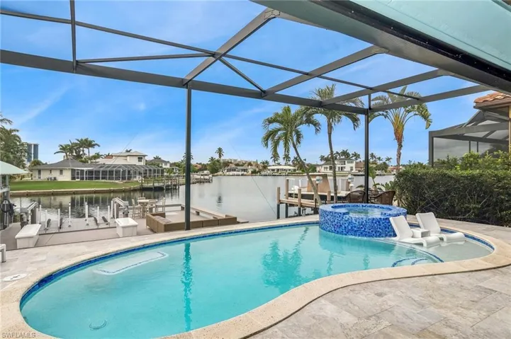 View of swimming pool with a lanai, a boat dock, a water view, and a patio