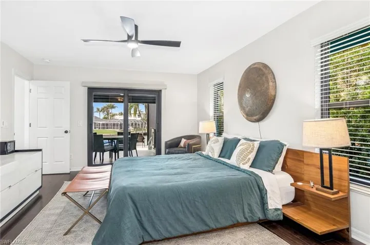 Bedroom with ceiling fan, dark hardwood / wood-style flooring, access to exterior, and multiple windows