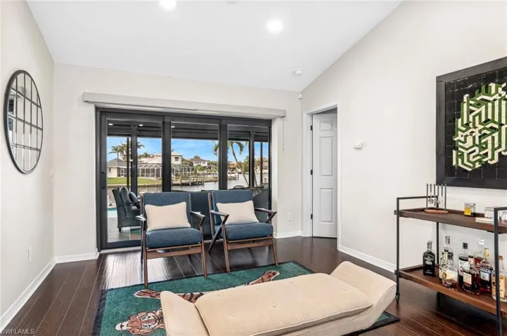 Sitting room with indoor bar, dark hardwood / wood-style floors, vaulted ceiling, and a water view