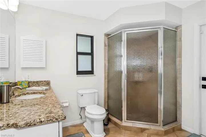Bathroom with tile patterned floors, vanity, walk in shower, and toilet