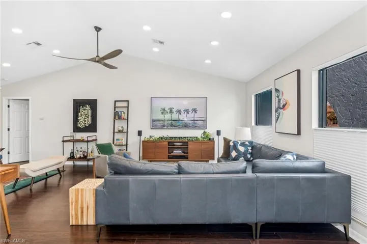 Living room with lofted ceiling, ceiling fan, and dark wood-type flooring