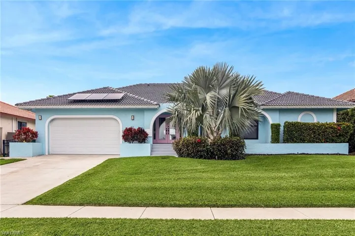 View of front of property featuring solar panels, a garage, and a front yard