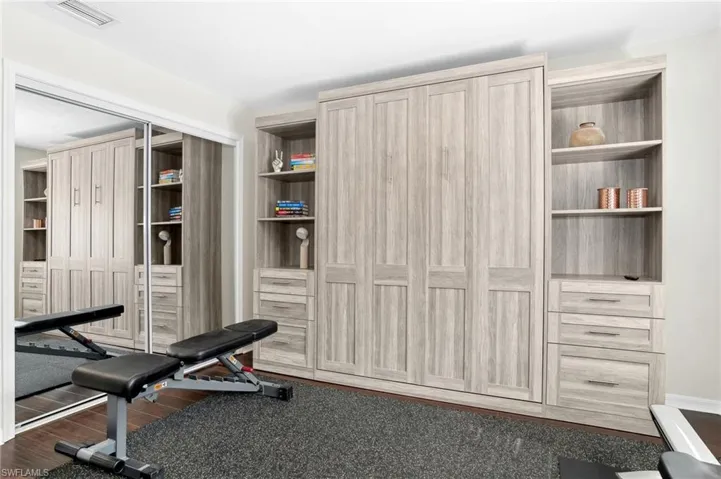 Workout area featuring built in features and dark hardwood / wood-style floors