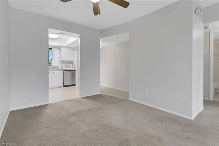 Unfurnished living room featuring ceiling fan and light carpet