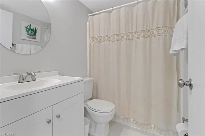 Full bathroom with vanity, toilet, shower / bathtub combination with curtain, and tile patterned floors